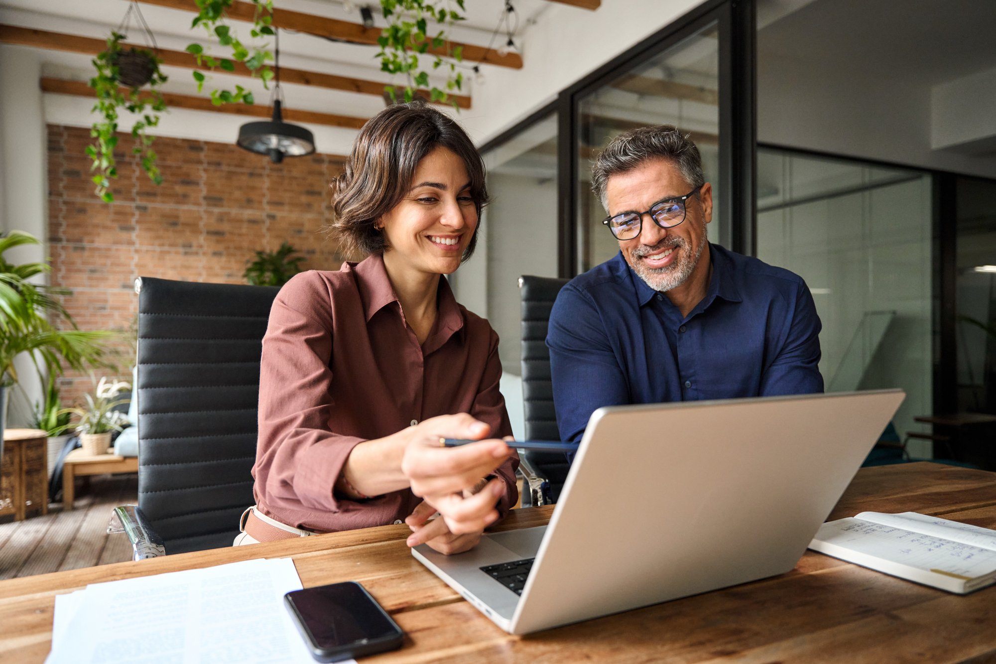 Business team of two executives working together using laptop in office