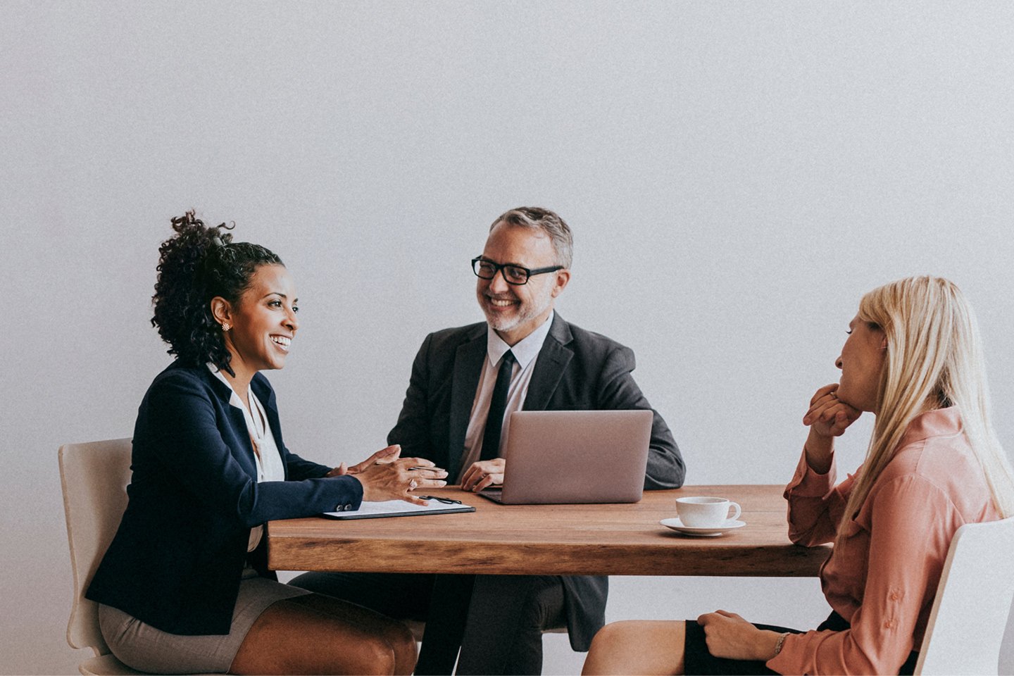 Three business professionals engaged in discussion while seated at a conference table.