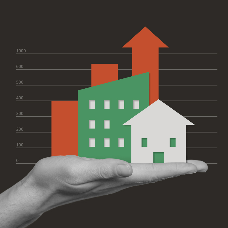An illustration of a hand holding an office building and a house, with a bar chart behind, set against a black background