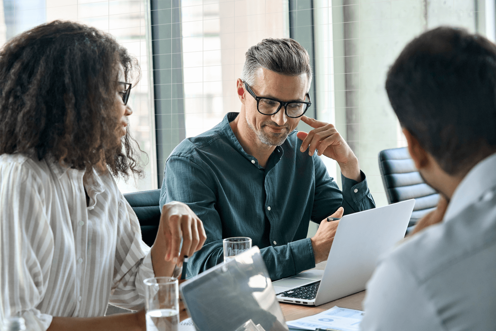 Office workers seated at a desk looking at a laptop