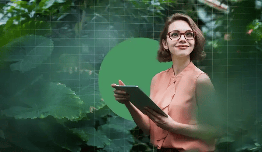 Woman with glasses holding a tablet in a greenhouse, surrounded by large green leaves and grid overlay.