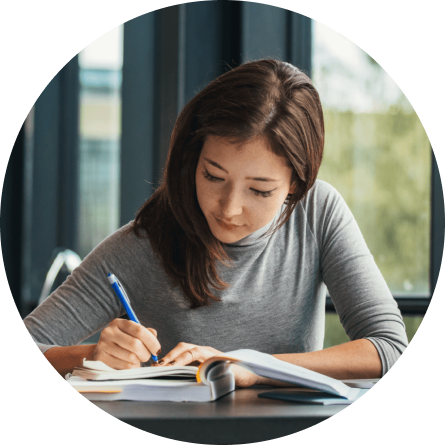 Image of a woman sitting at a desk, writing in a notebook