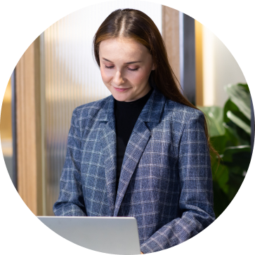 Image of a woman standing at a desk on a laptop