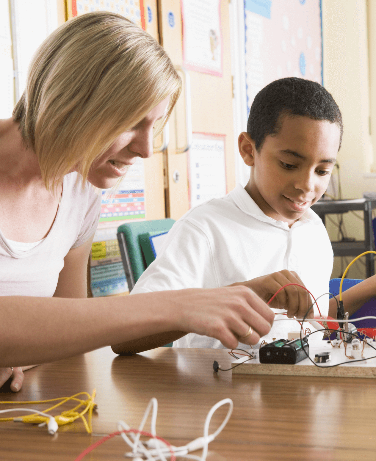 Female teacher showing a student how to use an electronic circuit board.